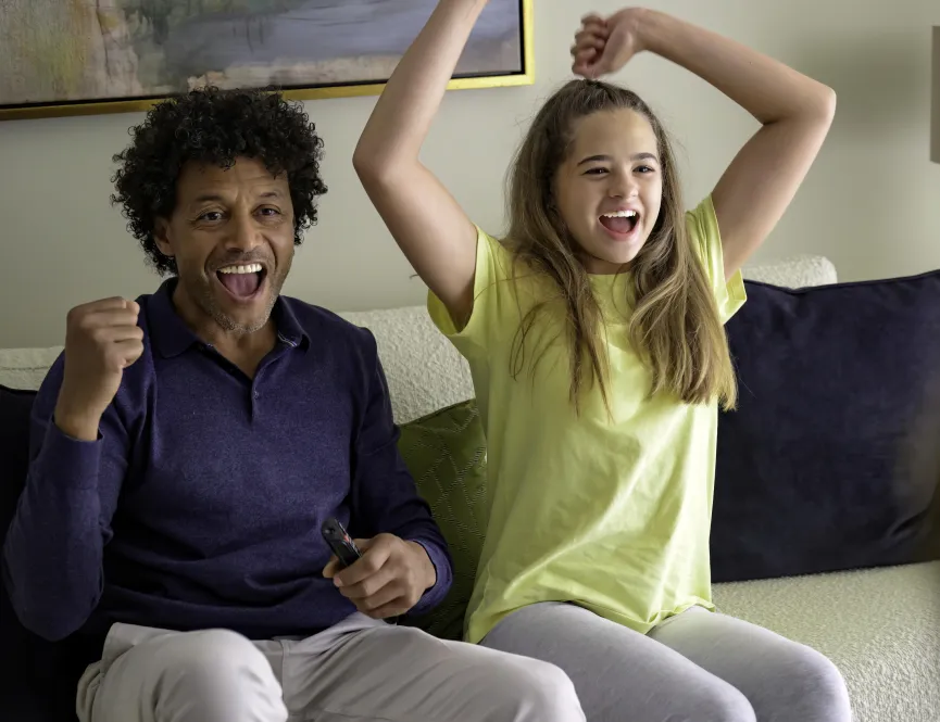dad and daughter cheering on sofa